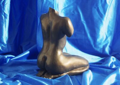 Escultura de mujer desnuda arrodillada