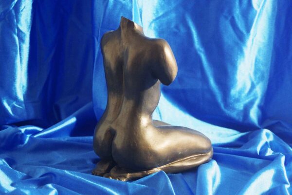 Escultura de mujer desnuda arrodillada
