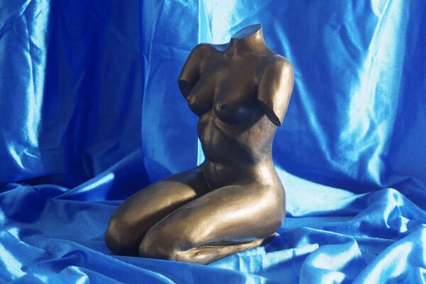 Escultura de mujer desnuda arrodillada