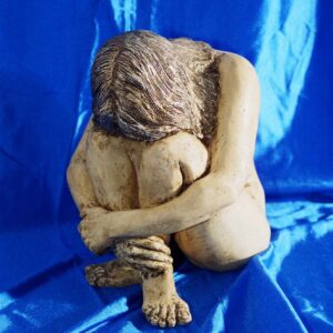 Escultura de una mujer desnuda sujetándose las piernas