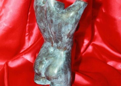 Escultura de una mujer desnuda con los brazos en alto
